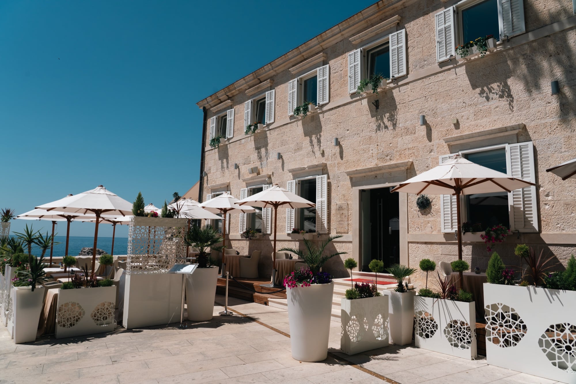 A cafe terrace with white umbrellas among the old stone buildings, Dubrovnik