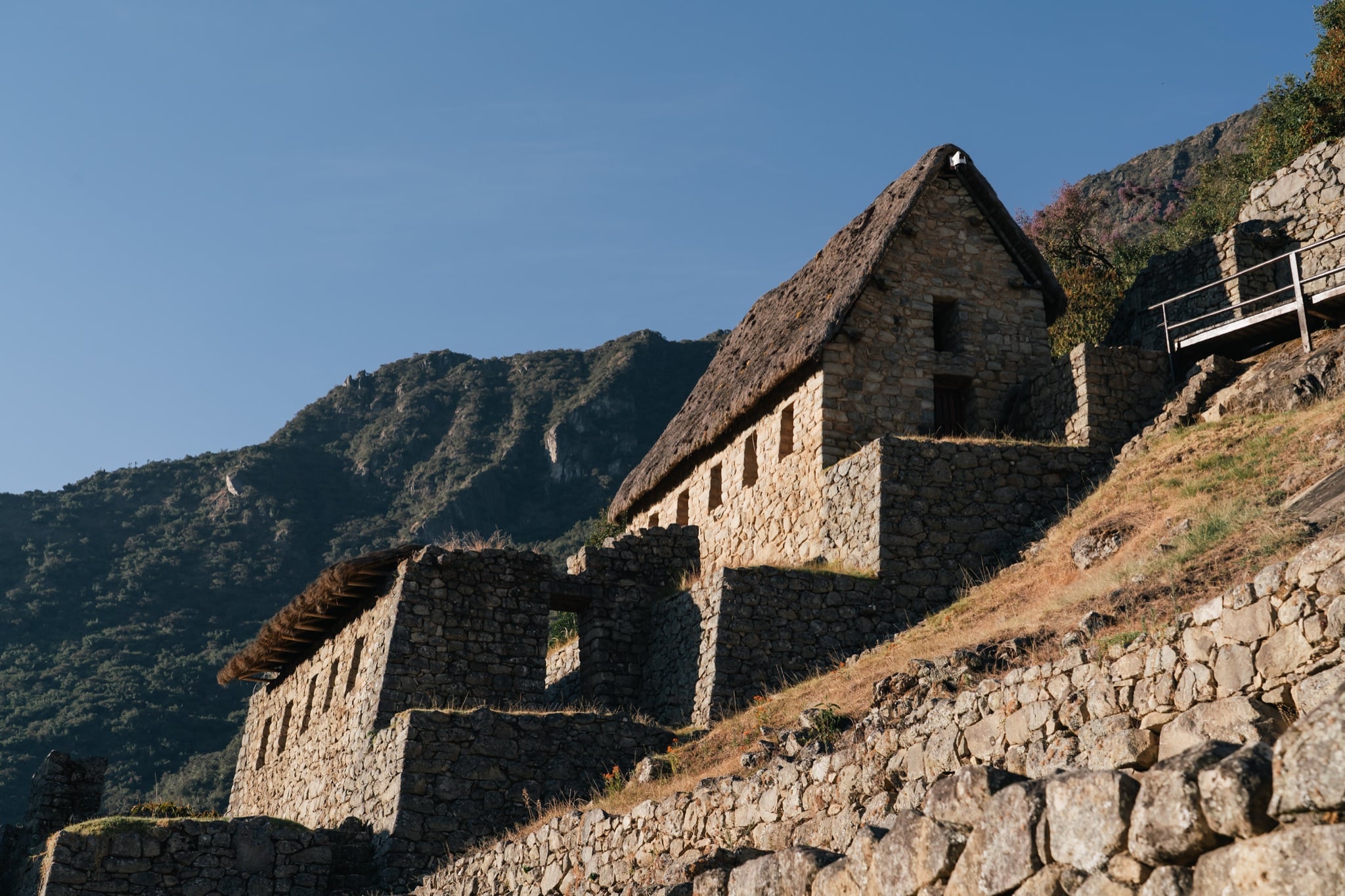 Stone house foundations along the ridge, mountains beyond