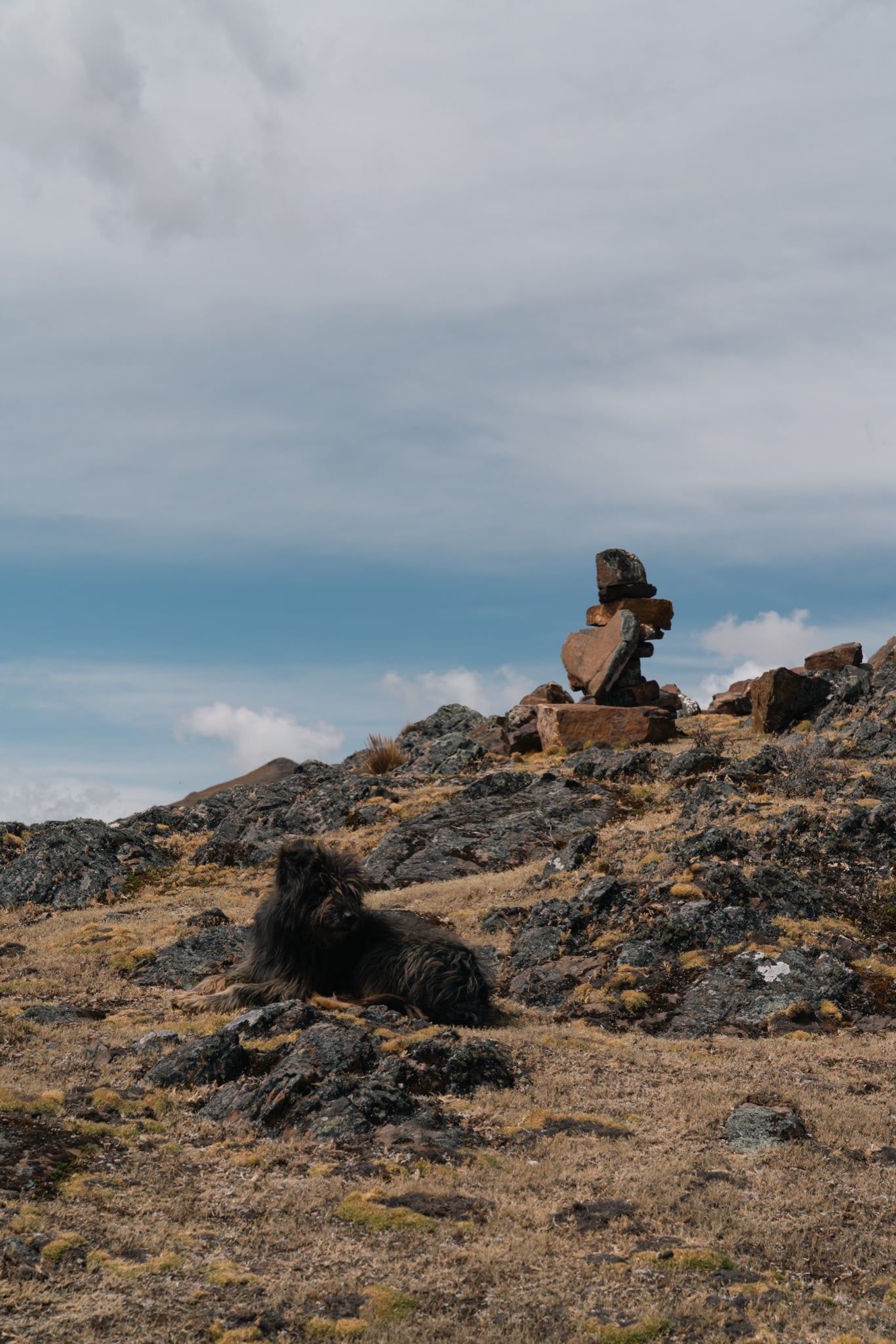 A hiker resting on a ridge above a mountain lake