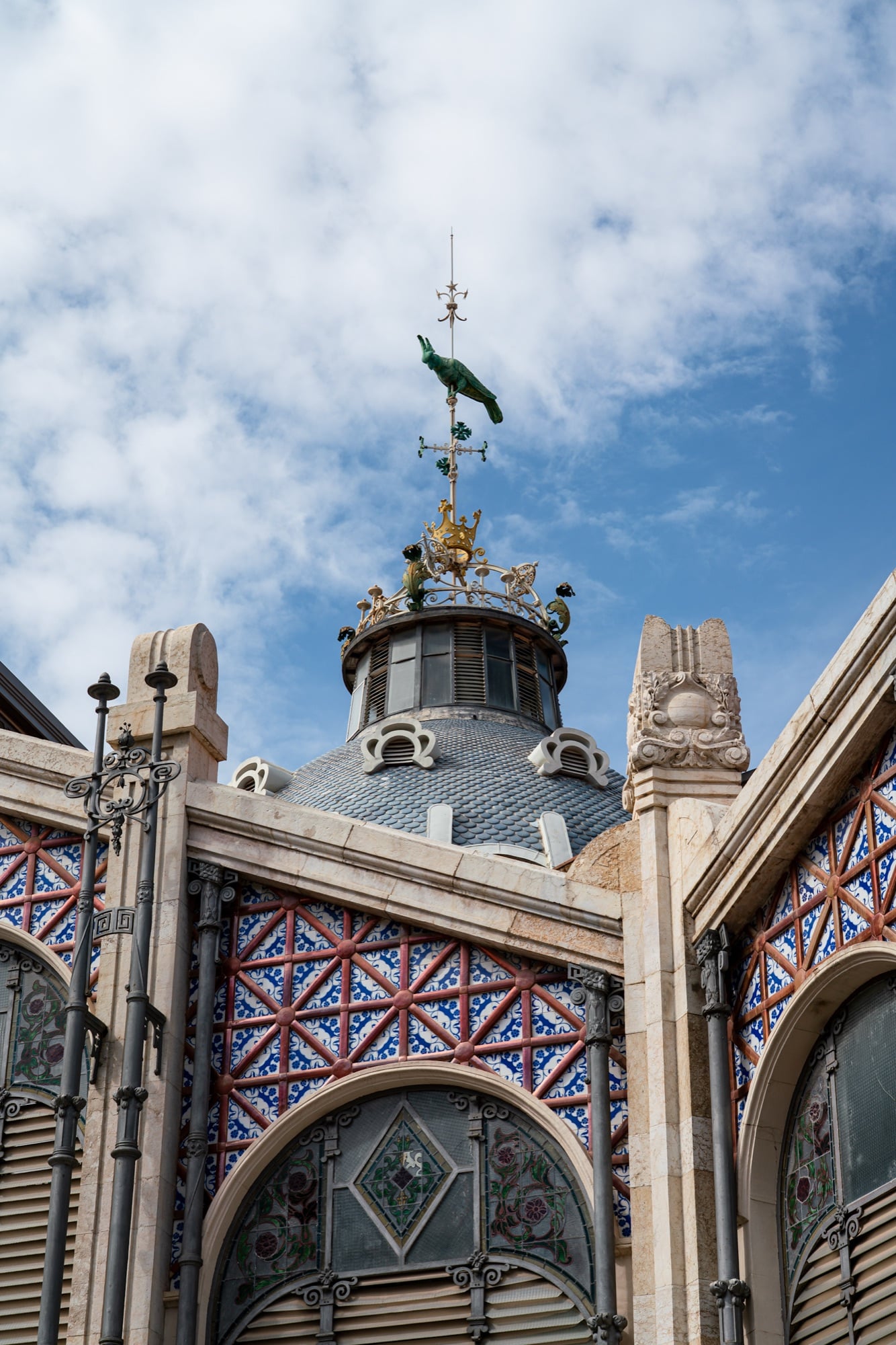 The Mercado Central's tiled dome and parrot weathervane above arches patterned in red and blue mosaic